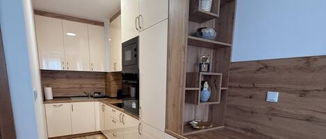 A modern kitchen with wooden cabinets, a built-in oven, and a wooden countertop.