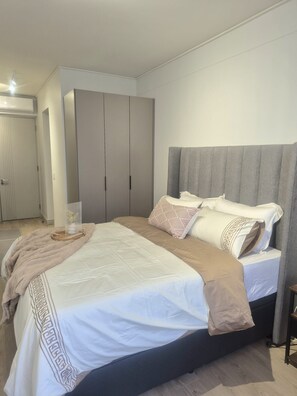 A bedroom with a bed, a wardrobe, and a bedside table. - Charming Studio in beautiful Johannesburg, perfect for your stay. (Johannesburg)