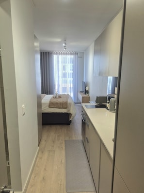 A compact hotel room with a bed, a small kitchenette, and a bathroom. - Charming Studio in beautiful Johannesburg, perfect for your stay. (Johannesburg)