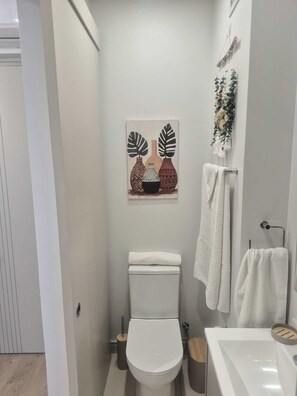 A modern bathroom with a toilet, sink, and decorative wall art. - Charming Studio in beautiful Johannesburg, perfect for your stay. (Johannesburg)