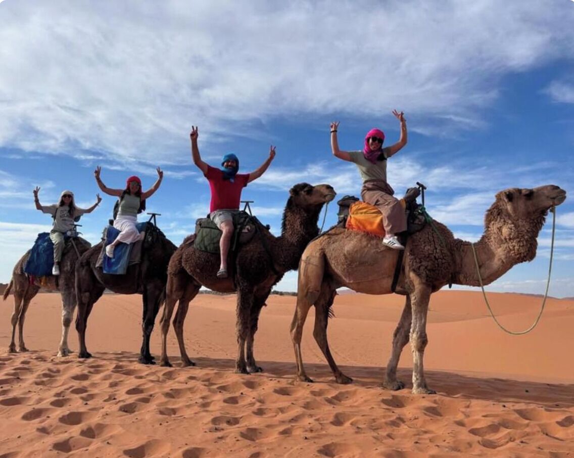 Un groupe de personnes chevauchant des chameaux dans un paysage désertique.