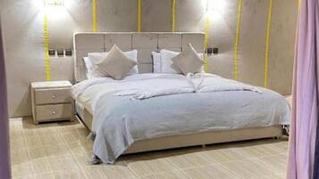 Un dormitorio con cama, mesita de noche e iluminación en la pared.