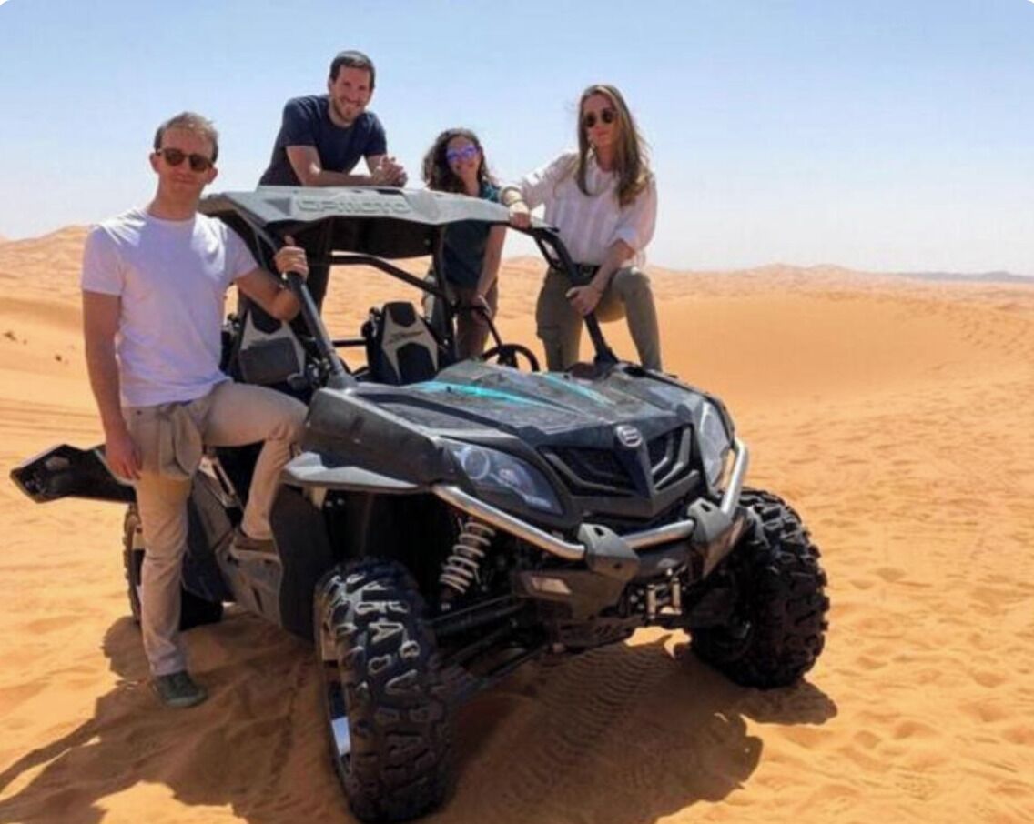A group of people on a dune buggy in a desert setting.