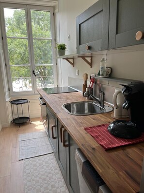 Una cocina con encimera de madera, pileta de acero inoxidable y cafetera.