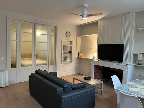 Una sala de estar con sofá, televisión, chimenea y ventilador de techo.