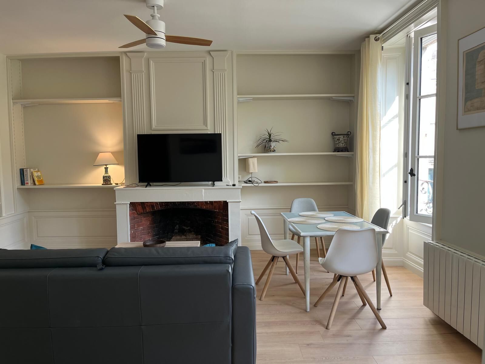 Un salon avec une cheminée, un téléviseur et un coin repas avec des chaises.
