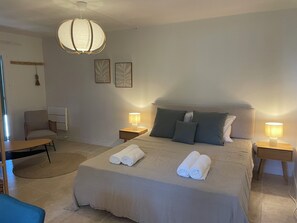 Ein Hotelzimmer mit einem großen Bett, zwei Nachttischlampen, einem Sessel und einem Schreibtisch.
