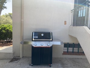 Ein tragbarer Weber Genesis Grill mit digitalem Display, vor einer Gebäudefassade platziert.
