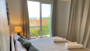 A hotel room with a bed, pillows, a lamp, and a view of the outdoors. - Luxury 8-person villa on the Côte d'Azur with a pool and ocean views from every room (Fréjus)