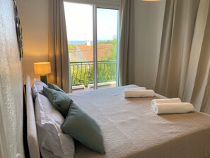 A hotel room with a bed, pillows, a lamp, and a view of the outdoors. - Luxury 8-person villa on the Côte d'Azur with a pool and ocean views from every room (Fréjus)