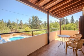 Ein Balkon mit Pool, Korbstühlen und Blick auf Bäume.