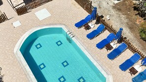 A rectangular swimming pool with a tiled deck, surrounded by lounge chairs and umbrellas. - Villa Oleander- with Private pool & Near the beach (Chania)