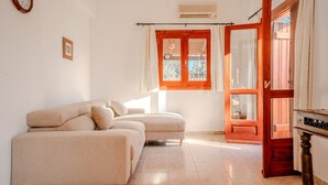 A room with a sofa, a wooden door, and a window with curtains. - Villa Oleander- with Private pool & Near the beach (Chania)