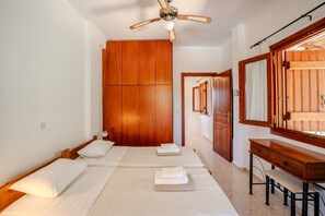 Ein Schlafzimmer mit einem Bett, einem Holzschrank, einem Schreibtisch und einem Spiegel.