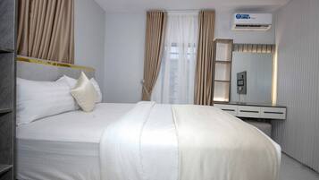 A modern hotel room with a large bed, a bedside table, a mirror, and an air conditioning unit.