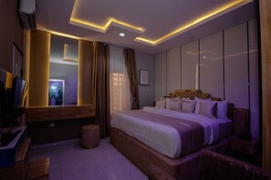 A modern hotel room with a large bed, a vanity with a mirror, and a television. - Orbit Meridian Leisure and Suites (Ota)
