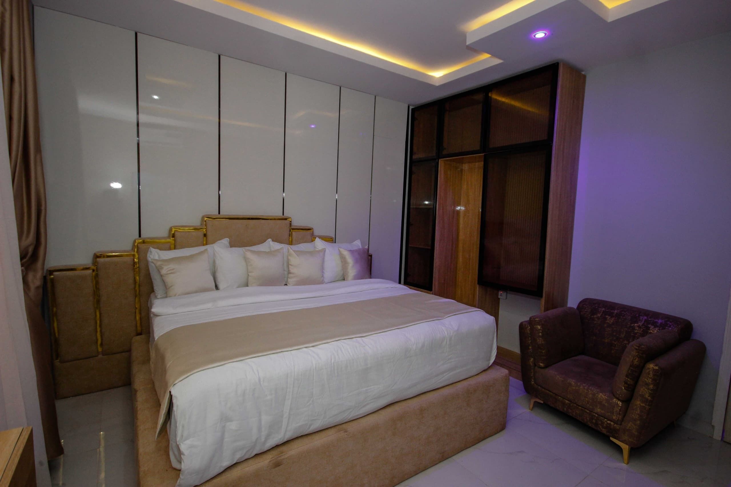 Um quarto moderno com uma cama grande, uma área de estar e um guarda-roupa.