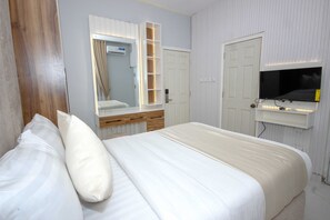 Makuuhuone, jossa on sänky, peili, seinälle asennettu televisio ja ovi.