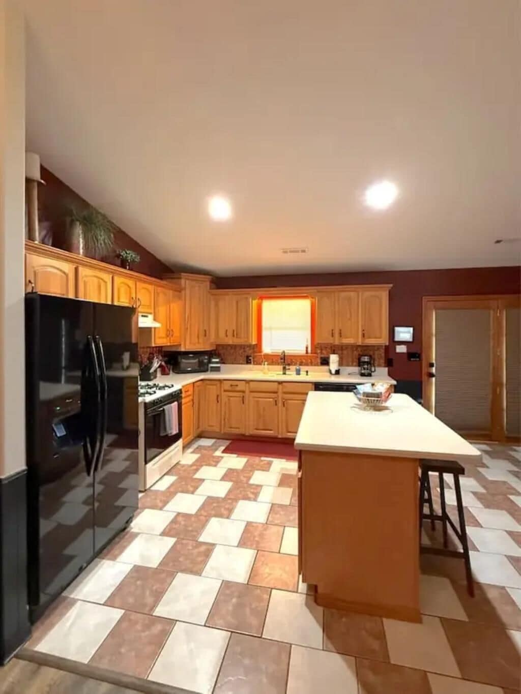 A kitchen with a central island, wooden cabinets, and a black refrigerator.