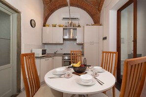 A dining area with a round table, chairs, and a bowl of fruit. - San Zanobi Central Stay (Florence)