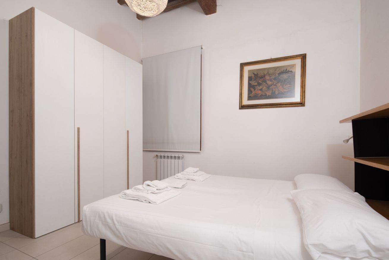 Une chambre à coucher avec un lit, une armoire, un radiateur et un tableau encadré au mur.