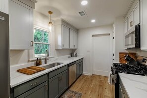 Una cocina moderna con armarios blancos, un lavamanos de acero inoxidable y una estufa a gas.