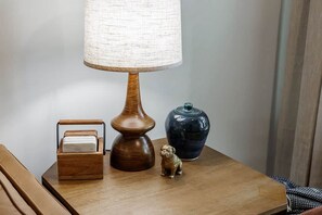 A bedside table with a lamp, a small wooden box, a ceramic vase, and a figurine.