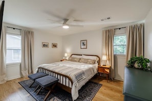 A bedroom with a bed, bedside tables, a ceiling fan, and a window with curtains.