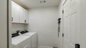 A laundry room with a washing machine, dryer, and a door with a handle. - Just off S. Milledge 3BD/2BA Pet Friendly with EV Charger (Athens)