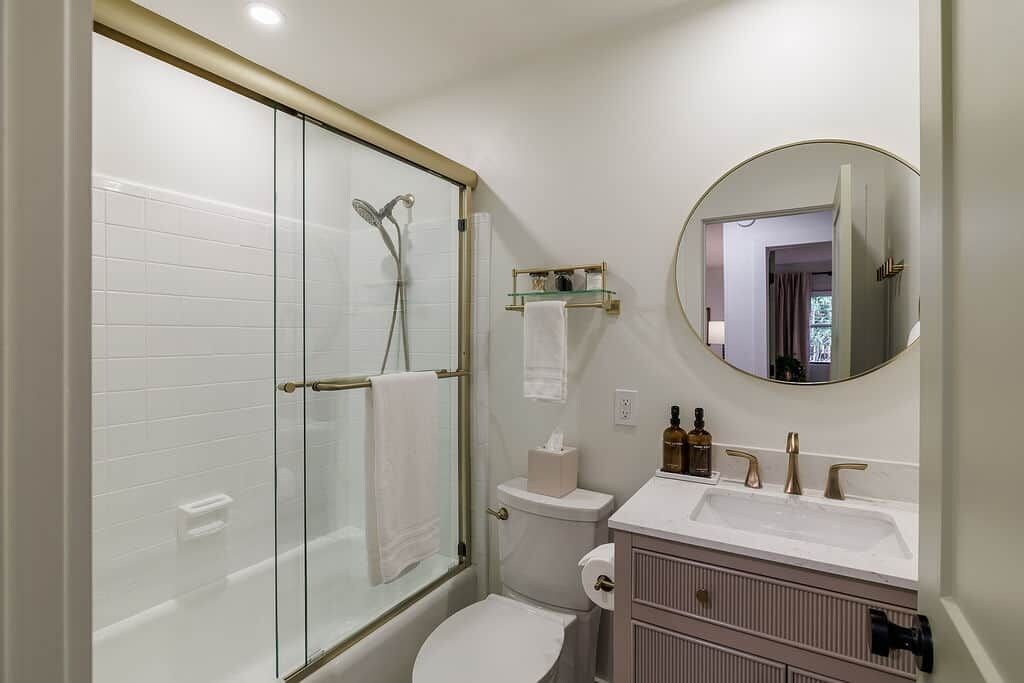 Une salle de bain moderne avec une douche à parois de verre, des toilettes, un lavabo avec un miroir et un meuble-lavabo avec espace de rangement.