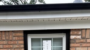 A brick wall with a window featuring a sign that reads 'PARK HERE'.