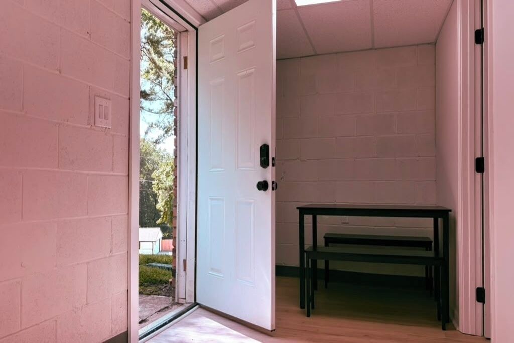 A room with a white door, a small table, and a bench.