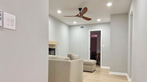 A modern living room with a ceiling fan, a sofa, and a dining area in the background.