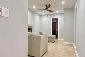 A modern living room with a ceiling fan, a sofa, and a dining area in the background.