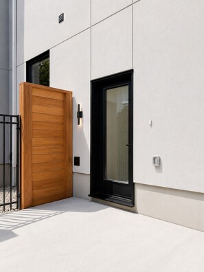 Un edificio moderno con una porta in legno, una finestra in vetro e un cancello in metallo.