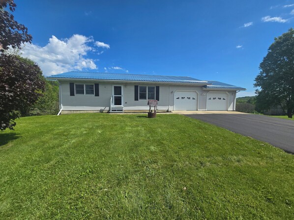 A single-story house with a blue roof, a front porch, and a garage.