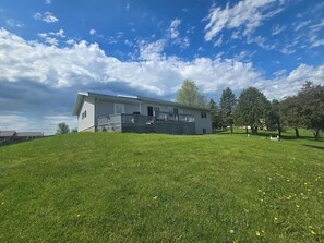 Ein einstöckiges Haus mit umzäuntem Garten, blauem Himmel und Bäumen im Hintergrund.