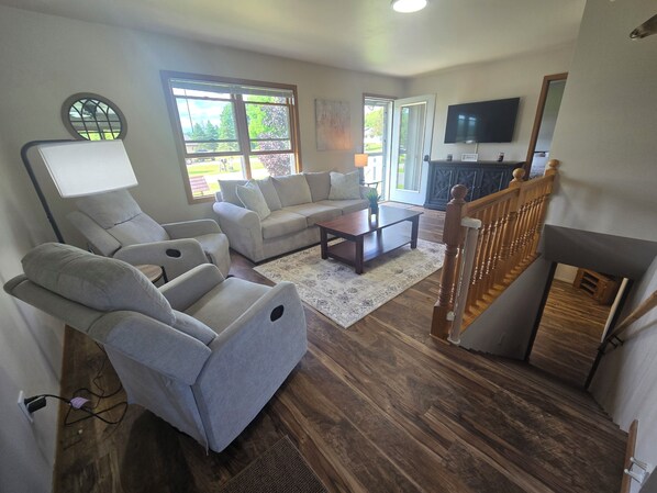 A living room with a sofa, two armchairs, a coffee table, and a TV.