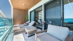 A modern balcony with a glass railing, a wooden ceiling, and a view of a building with balconies. - 3-bedroom luxury beachfront condo - Encantame Soleil with lazy river, waterslide (Puerto Penasco, Son)