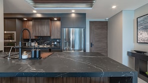 A modern kitchen with a marble countertop, stainless steel appliances, and wooden cabinetry. - 3-bedroom luxury beachfront condo - Encantame Soleil with lazy river, waterslide (Puerto Penasco, Son)
