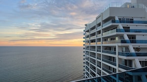 A multi-story building with balconies overlooking a body of water during sunset. - 3-bedroom luxury beachfront condo - Encantame Soleil with lazy river, waterslide (Puerto Penasco, Son)