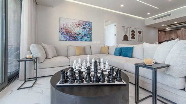 A modern living room with a large chessboard centerpiece, a sofa with multiple cushions, and abstract art on the walls. - 3-bedroom luxury beachfront condo - Encantame Soleil with lazy river, waterslide (Puerto Penasco, Son)