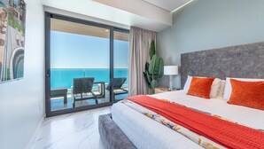 A hotel room with a large bed, a view of the sea, a balcony with chairs, and a plant. - 3-bedroom luxury beachfront condo - Encantame Soleil with lazy river, waterslide (Puerto Penasco, Son)