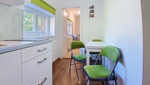 A narrow hallway with a window, a white cabinet with drawers, and two green chairs. - Černý Důl by Interhome (Cerny Dul)