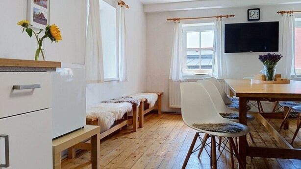 Ett rum med en säng, ett skrivbord, en stol, en tv och ett fönster med gardiner.