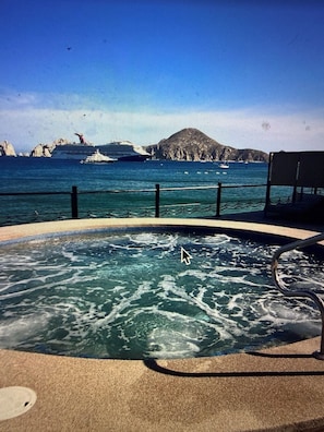 Une piscine avec vue sur la mer et les bateaux, une chaise et une clôture.