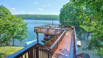 A wooden deck with a view of a lake, surrounded by trees.