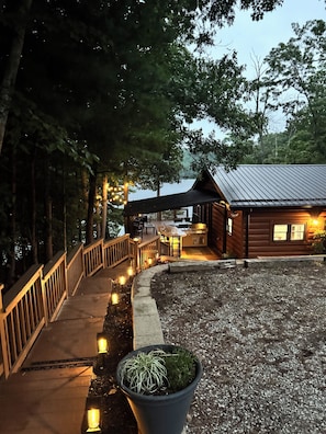 A wooden cabin with a deck, outdoor seating, and a grill area.