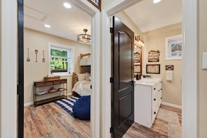 A bedroom with a bed, a nightstand, a dresser, a window, and a door.