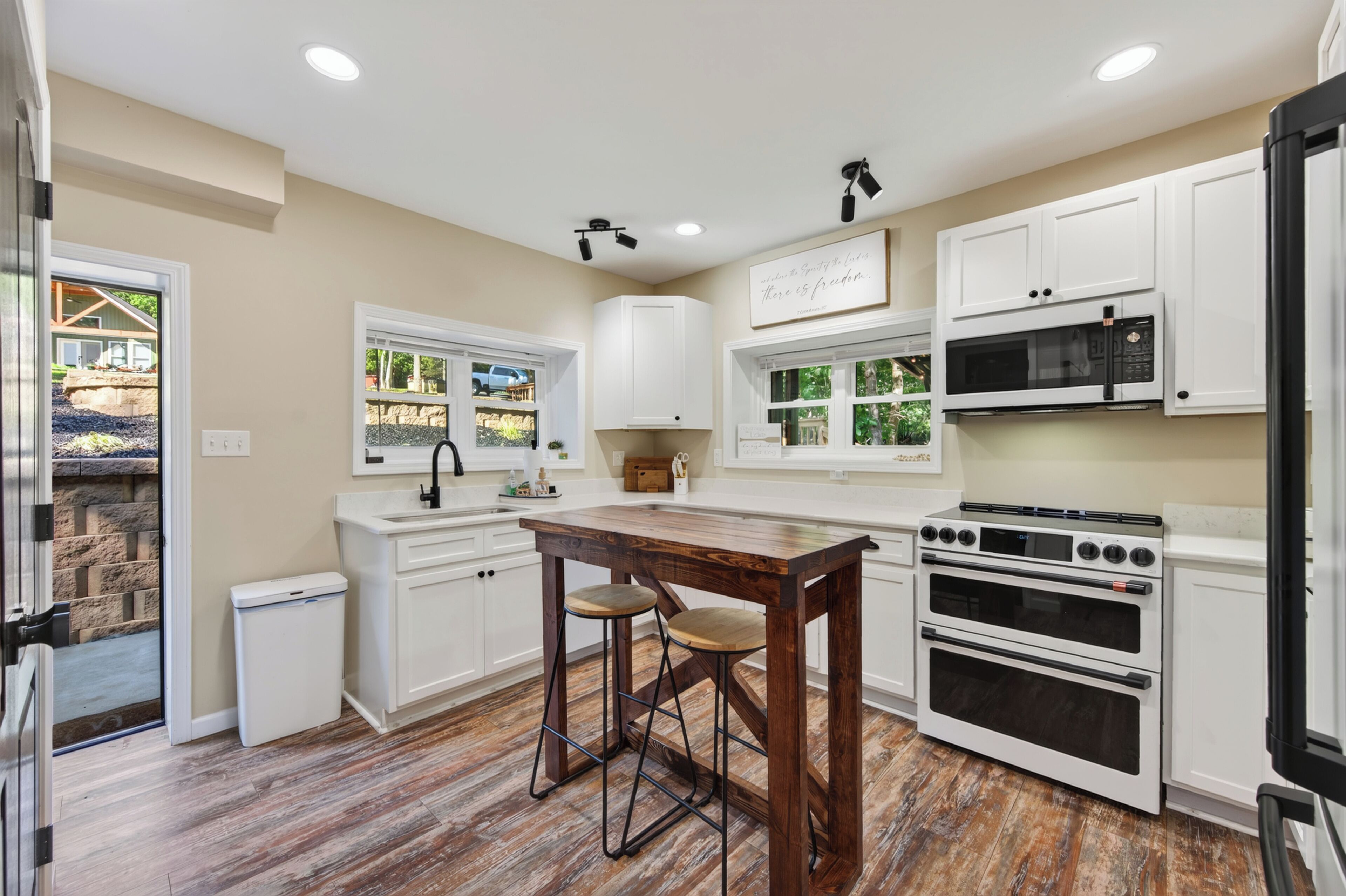 A modern kitchen with white cabinetry, a wooden dining table, and a built-in oven.